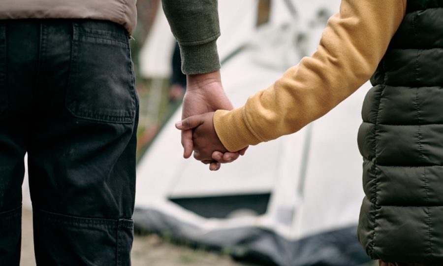 holding-hand-of-child-against-migrant-camp